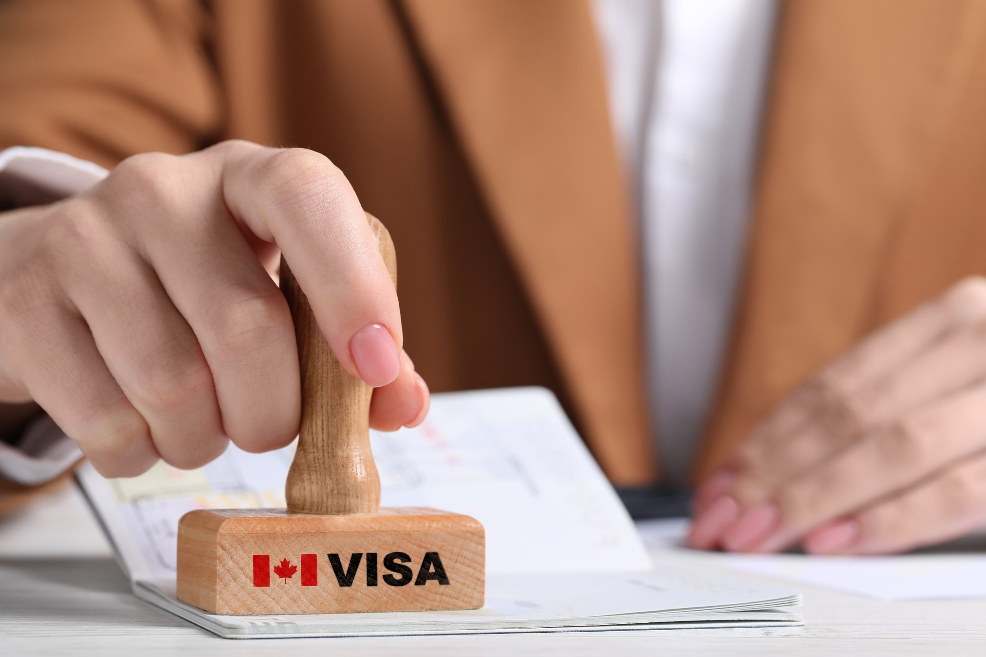 Woman Stamping Document at White Wooden Table, Closeup. Visa for Canada